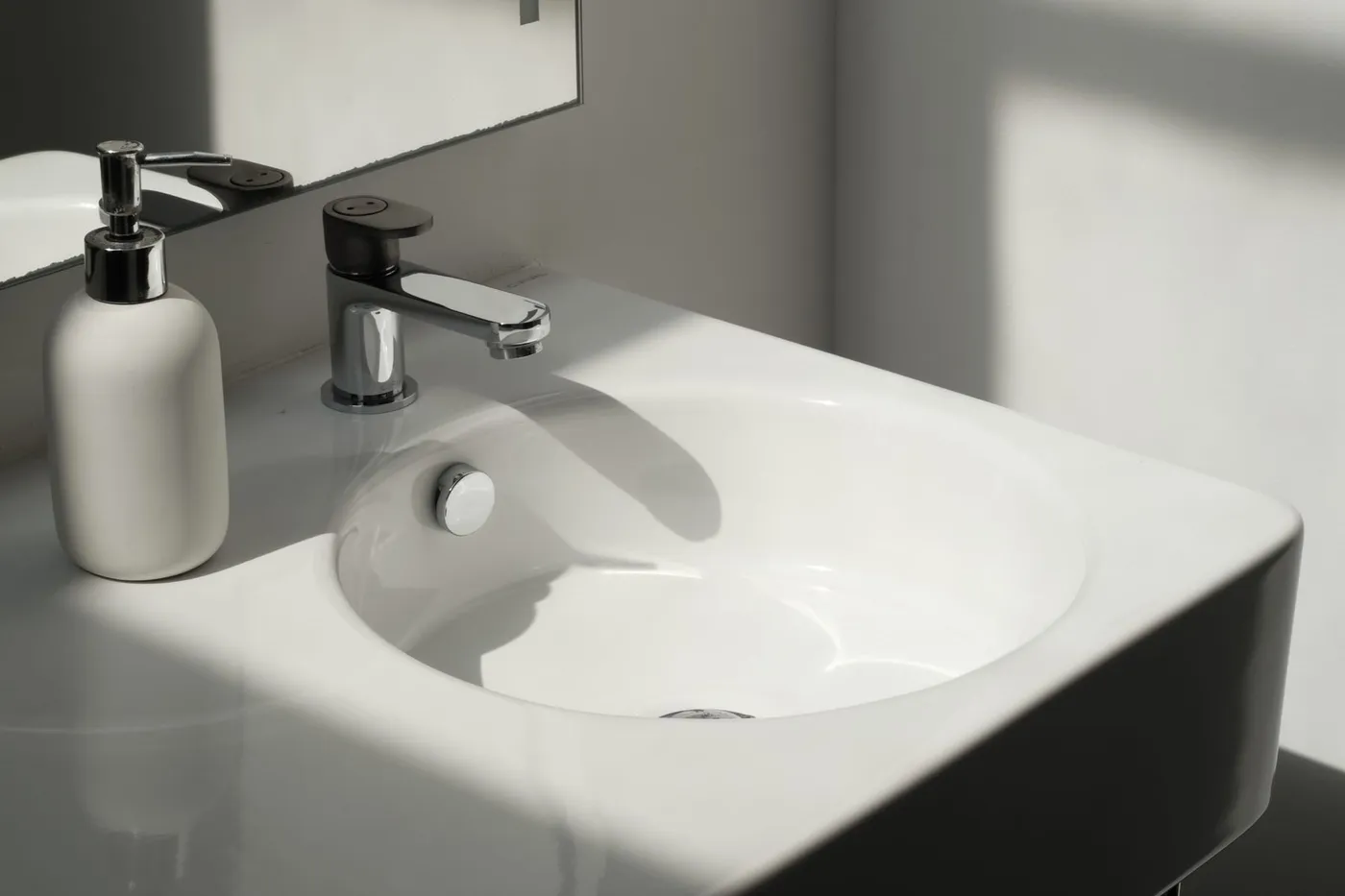 White basin with chrome faucet and soap dispenser